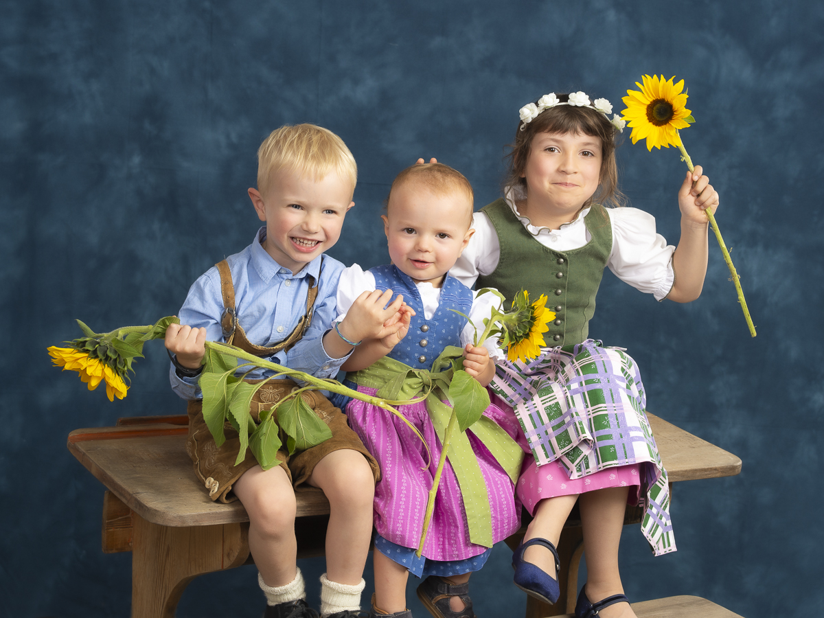 3 Kinder auf einer alten Schulbank mit Sonnenblumen
